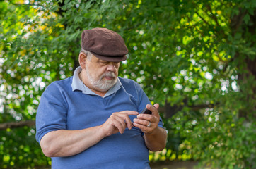 Naklejka na ściany i meble Portrait of bearded senior man using cellular phone outdoor