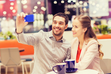 happy couple with smartphone taking selfie in mall