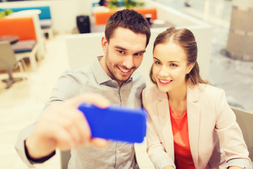 happy couple taking selfie with smartphone in cafe
