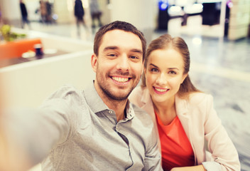 happy couple taking selfie in mall or office