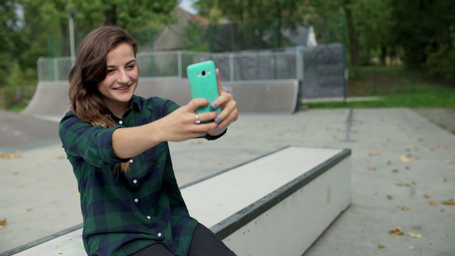 Girl doing selfies on smartphone in skate park
