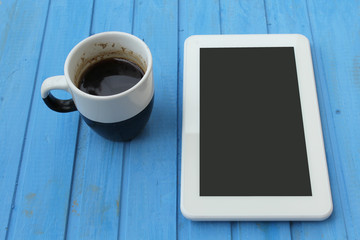 Fototapeta na wymiar Touch screen tablet computer and cup of coffee on blue background