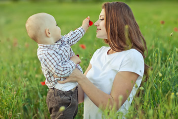 beautiful happy mother with her baby in a green field 