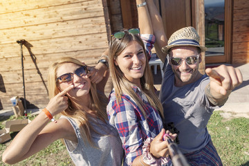 group of smiling friends taking funny selfie with smart phone