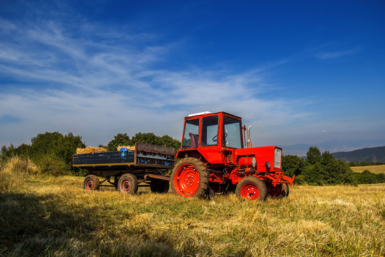 Old red tractor on the agricultural field