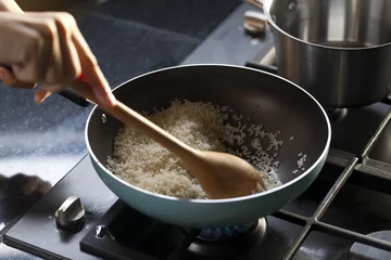 Crédence de cuisine en verre imprimé Cuisinier faire cuire du riz dans une poêle