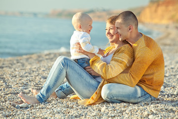 Happy family are playing with son on the beach 