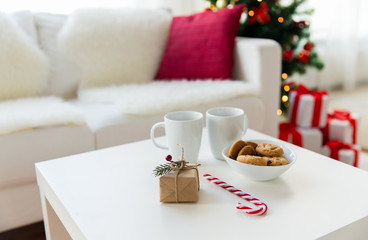 close up of gift, sweets and cups on table at home