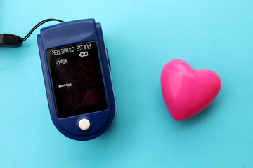 Pulse sensor used to measure pulse rate and oxygen levels and heart on blue background