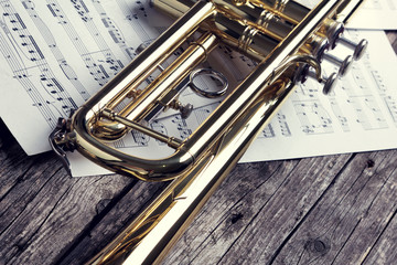 Trumpet and sheet music on old wooden table. Vintage style.