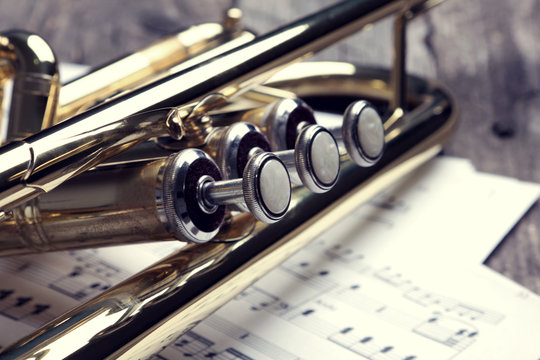 Trumpet and sheet music on old wooden table. Vintage style.