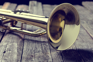 Trumpet on an old wooden table. Vintage style. - obrazy, fototapety, plakaty