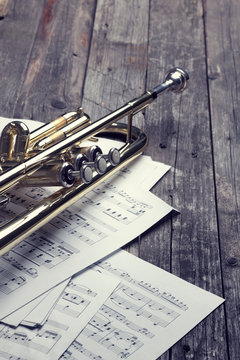 Trumpet and sheet music on old wooden table. Vintage style.