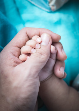 Pure love. Father holding a baby's hand with gently also baby holding a parent's thumb. close-up shot.