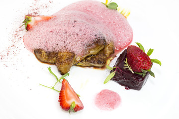 Roast goose liver is decorated with greens and strawberries