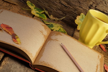 notebook and coffee on wooden table decorated with autumn leaves