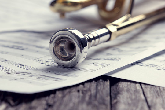 Trumpet and sheet music on old wooden table. Vintage style.