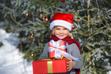 Cute  little boy with christmas gifts im winter forest