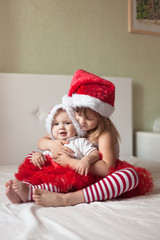 Children in pajamas and Christmas caps playing on the bed