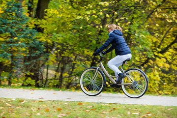 Fototapeta premium Urban biking - woman riding bike in city park 