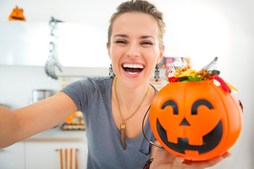 Happy woman making selfie with halloween bucket full of candy © Alliance