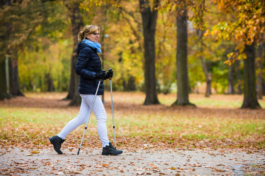 Nordic walking - middle-age woman working out in city park