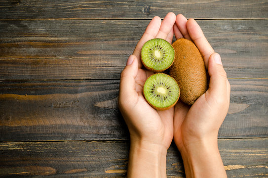 Kiwi fruit hold by hand on wooden background