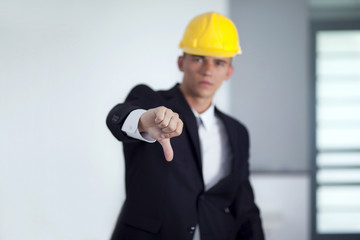 Young businessman wearing a safety hat and hand gesturing thumbs