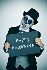 man with calaveras makeup and signboard with text happy hallowee
