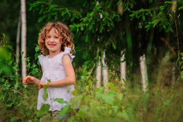 child girl exploring nature on the walk in summer forest on vacation