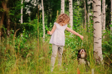 child girl playing with her dog in summer forest