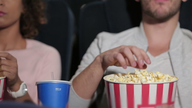 Couple in cinema theater eating popcorn