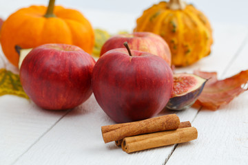 Apples, cinnamon and pumpkins on wodden table.