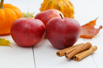 Apples, cinnamon and pumpkins on wodden table.