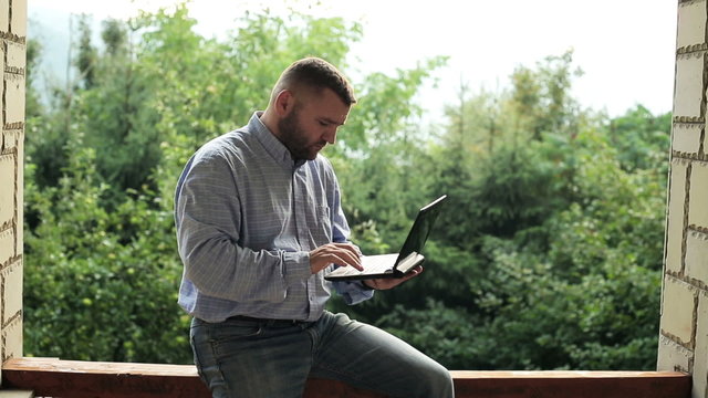 Young man with laptop on terrace
