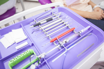 Different dental instruments over patient sitting in a pink dent - 94221145