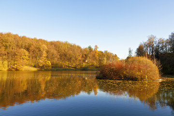 Fototapeta na wymiar Autumn landscape on a sunny day with the pond and the small island in Tsaritsyno, Moscow, Russia