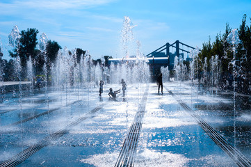Alley of fountains and children silhouette against the bright su