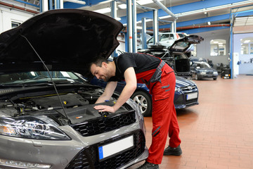 Mechaniker in einer Autowerkstatt repariert ein Fahrzeug // car repair shop