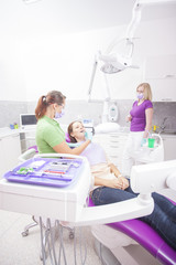 Female dentist and her assistant take jaw x-ray of female patien