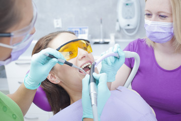 Female dentist and her female assistant working on teeth of wome - 94226360