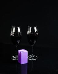 glass of wine and a candle on a black background