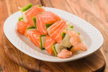 skewers of salmon and vegetables in white porcelain tray on eleg