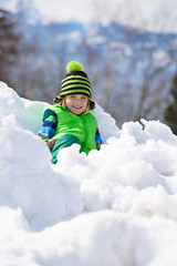Fototapeta na wymiar Little happy boy has fun witn snow outdoors