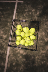 Paddle tennis basket in court with balls.