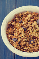 granola on white bowl on blue wooden background