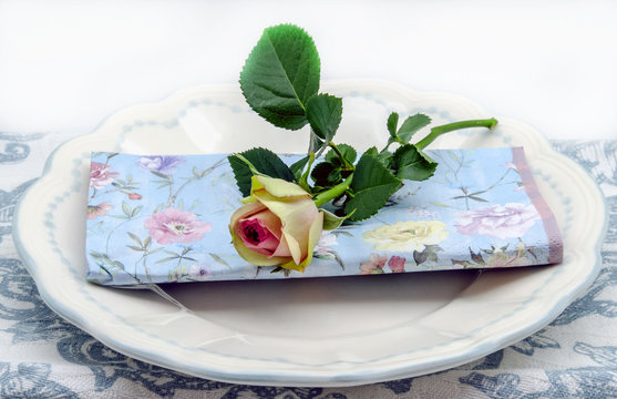 Decoración de mesa con platos,servilletas y una rosa 