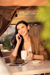 Pretty young business woman in a cafe drinking tea and talking o