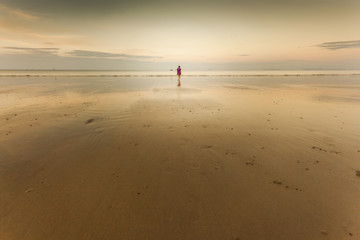 Lonley woman walking on the beach over sunset - obrazy, fototapety, plakaty