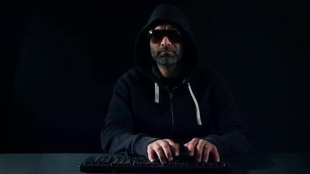 Hacker typing on keyboard in black room